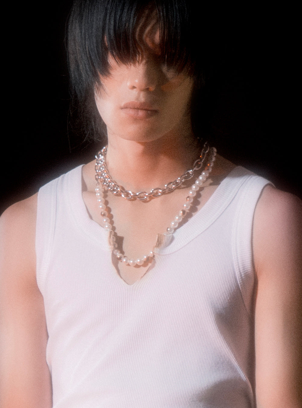 a young man wearing a white tank top and MIDNIGHTFACTORY Burnt pearls with chain necklace.