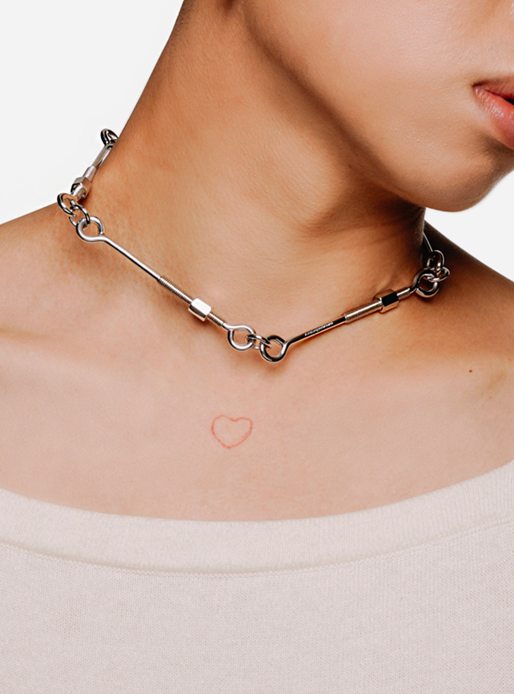 A woman wearing a MIDNIGHTFACTORY Screw-bolts bar necklace with a heart on it.
