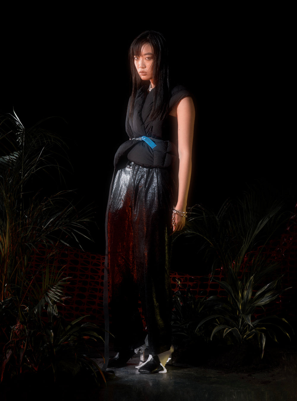 A woman in a black outfit standing in front of plants wearing the MIDNIGHTFACTORY Burnt pearls with paper-clip necklace/bracelet.