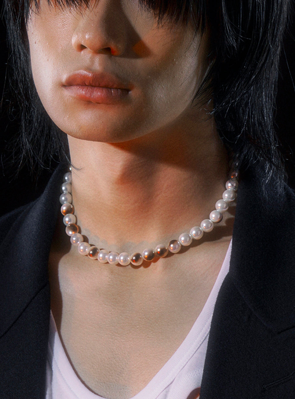 a man in a black jacket with a MIDNIGHTFACTORY Burnt pearls necklace.
