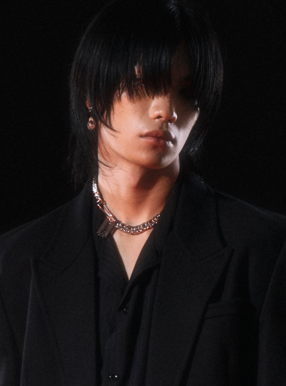 a young man in a black suit with a Burnt pearls with MNFT blade chain necklace by MIDNIGHTFACTORY.