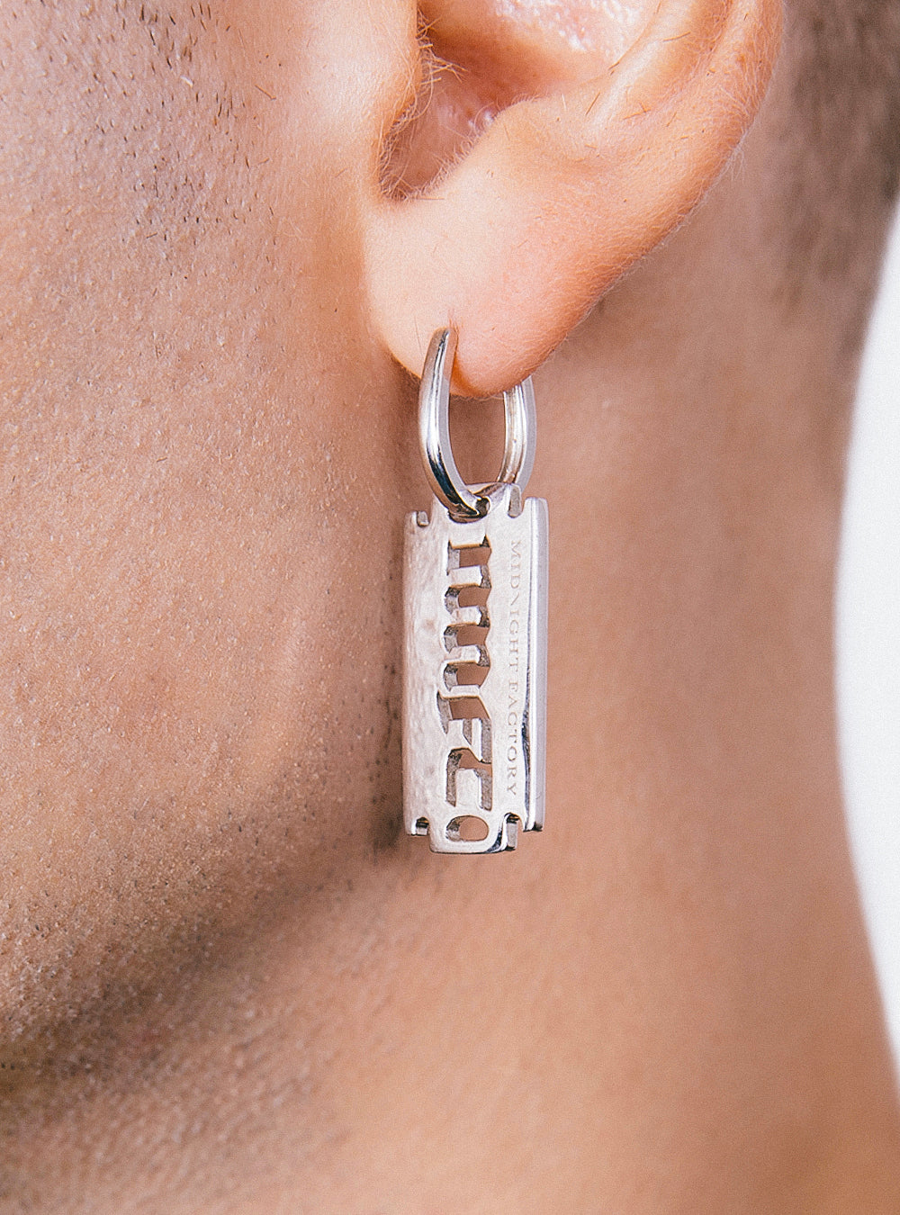 A man wearing a pair of MIDNIGHTFACTORY MNFT blade earrings.