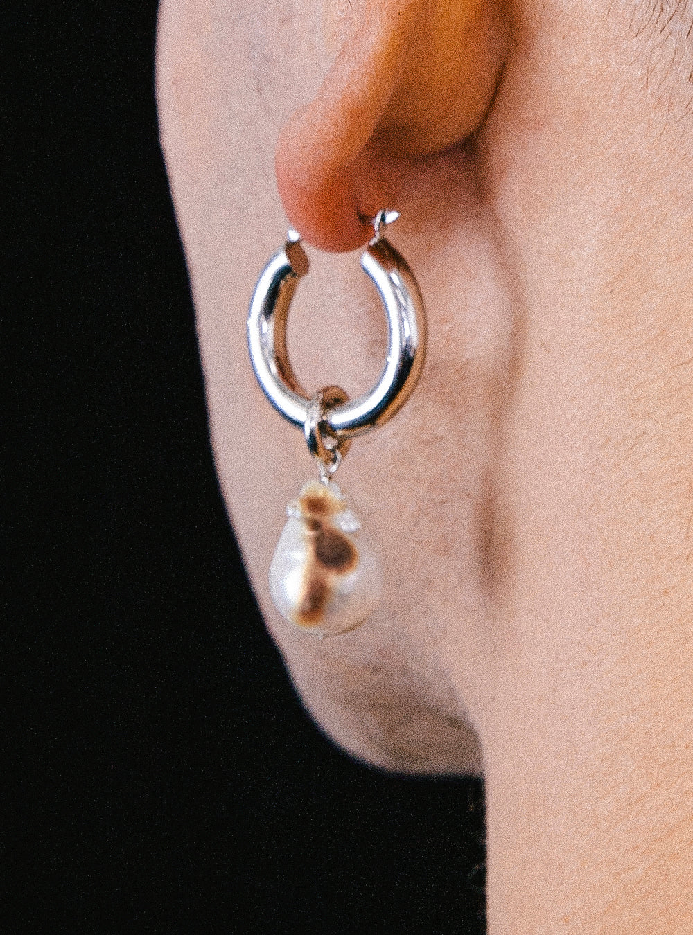 a man's ear with a MIDNIGHTFACTORY Burnt baroque pearl earring.