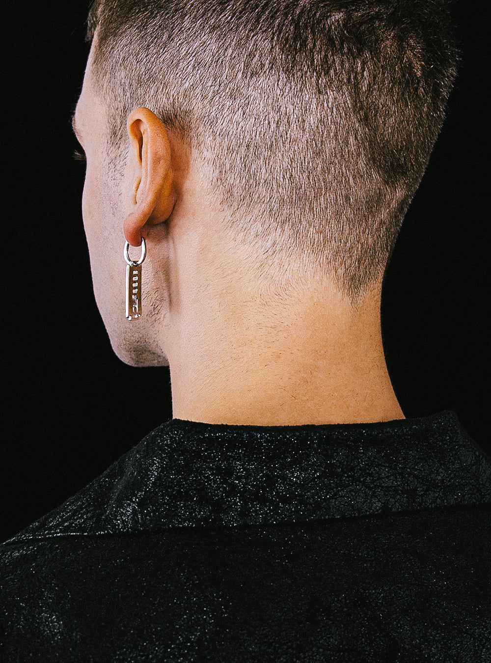 the back of a man wearing a pair of MIDNIGHTFACTORY MNFT blade earrings.