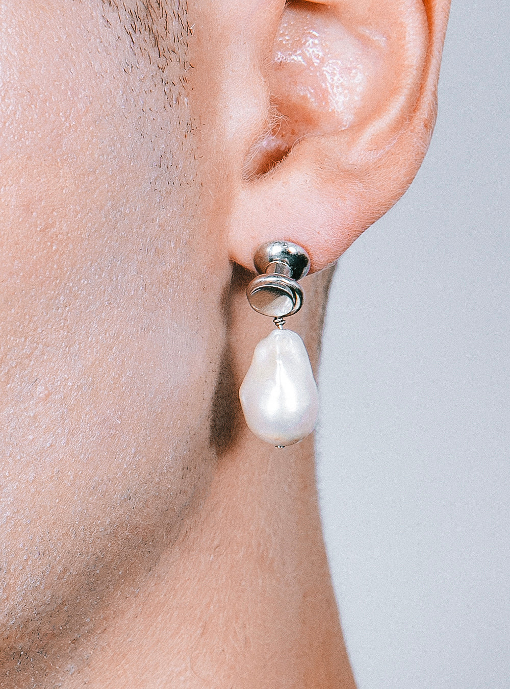 A man wearing a pair of MIDNIGHTFACTORY Baroque-pearl with push-pin earrings.