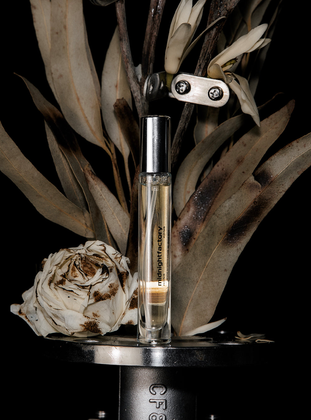 a bottle of MIDNIGHTFACTORY's GARDENASH Eau de Parfum sitting on top of a flower.