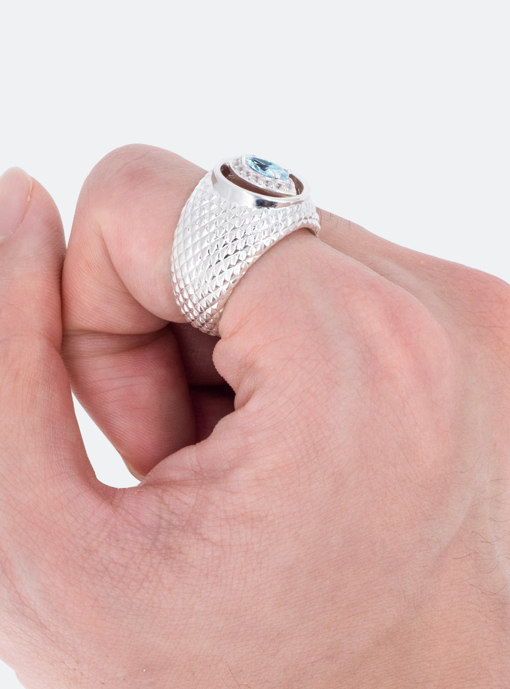 A man's hand holding a MIDNIGHTFACTORY Cat-eye cutout cocktail signet ring with a blue topaz stone.