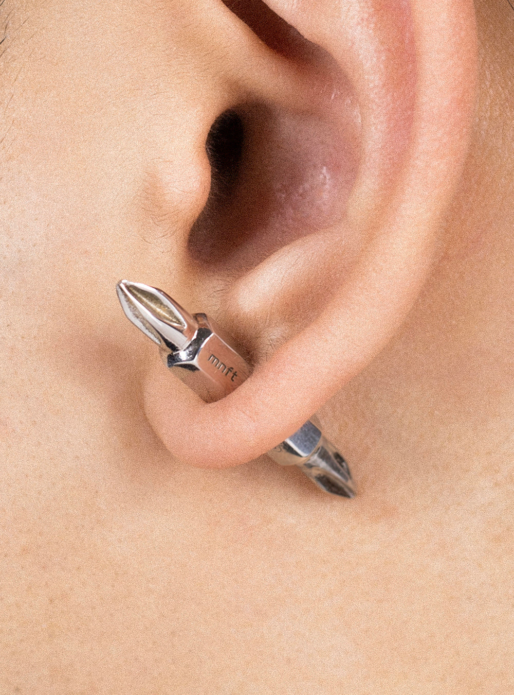 A woman's ear with a MIDNIGHTFACTORY Dual-driverbits earring.