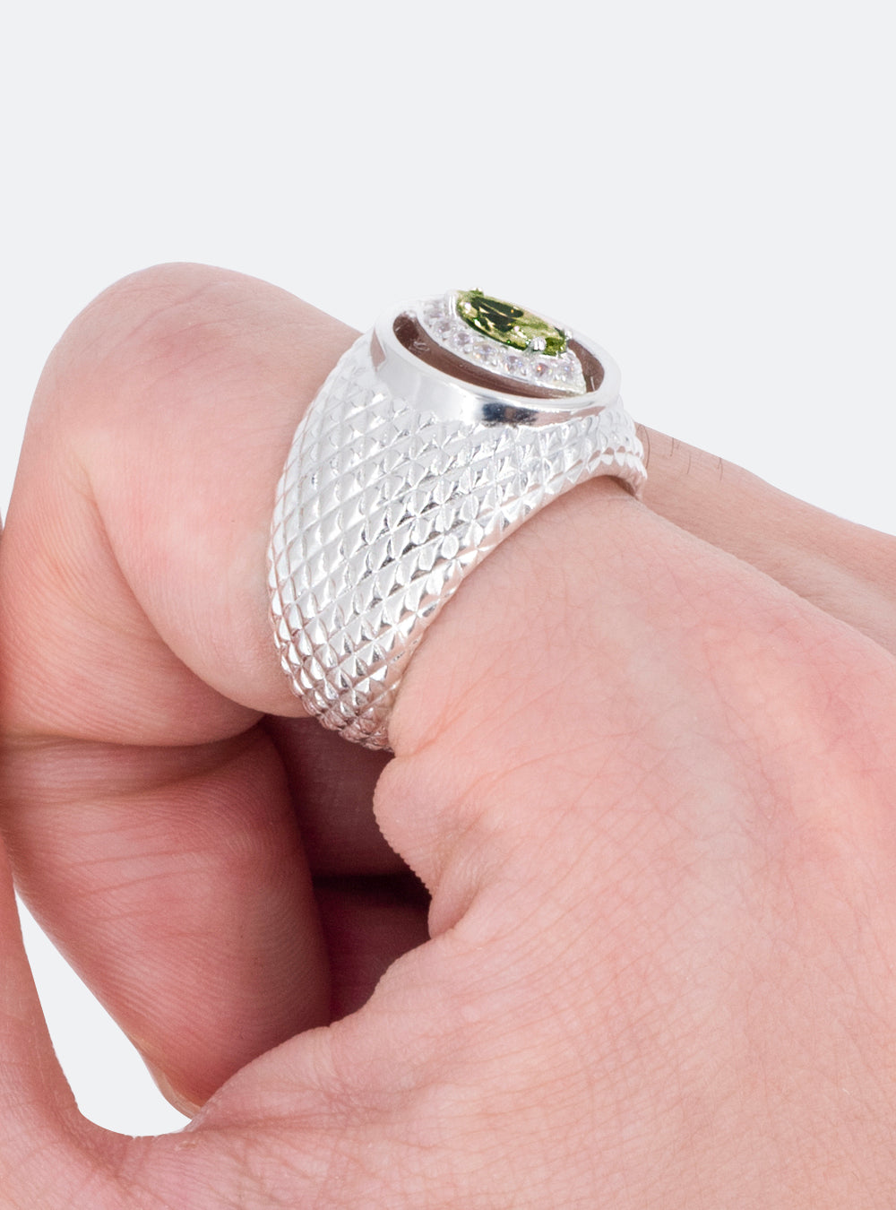 A man's hand holding a MIDNIGHTFACTORY Cat-eye cutout cocktail signet ring with a peridot stone.