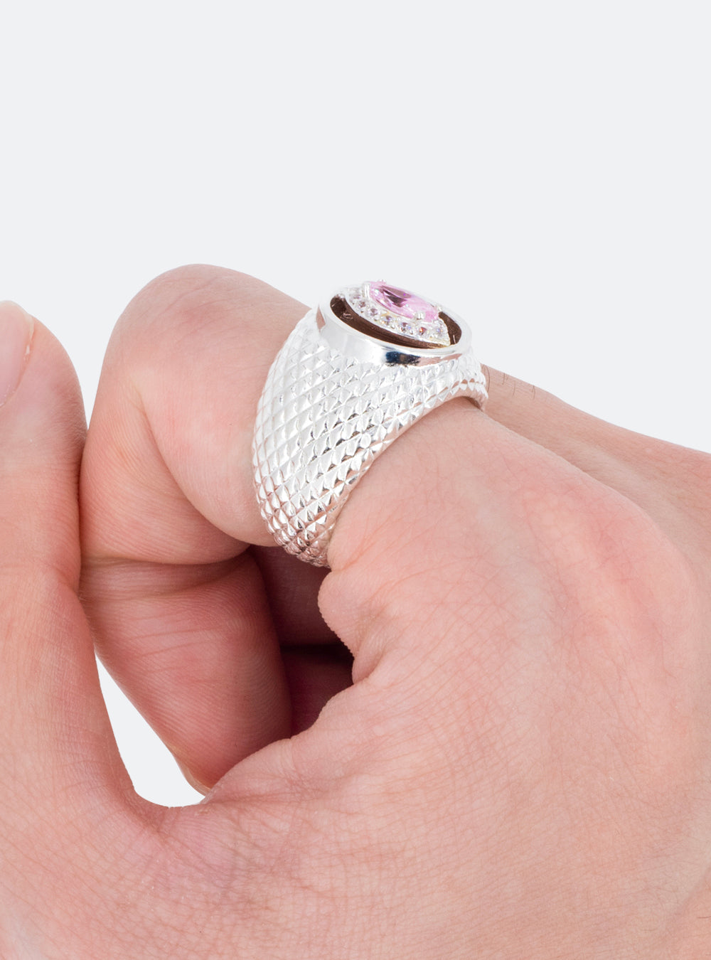 A woman's hand holding a MIDNIGHTFACTORY Cat-eye cutout cocktail signet ring with a pink stone.