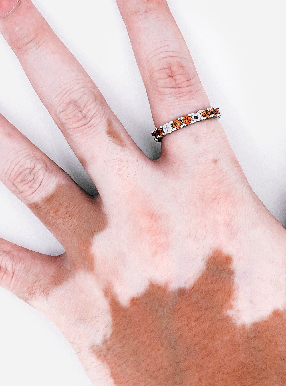 A woman's hand with a MIDNIGHTFACTORY Broken eternity ring with sapphire on it.
